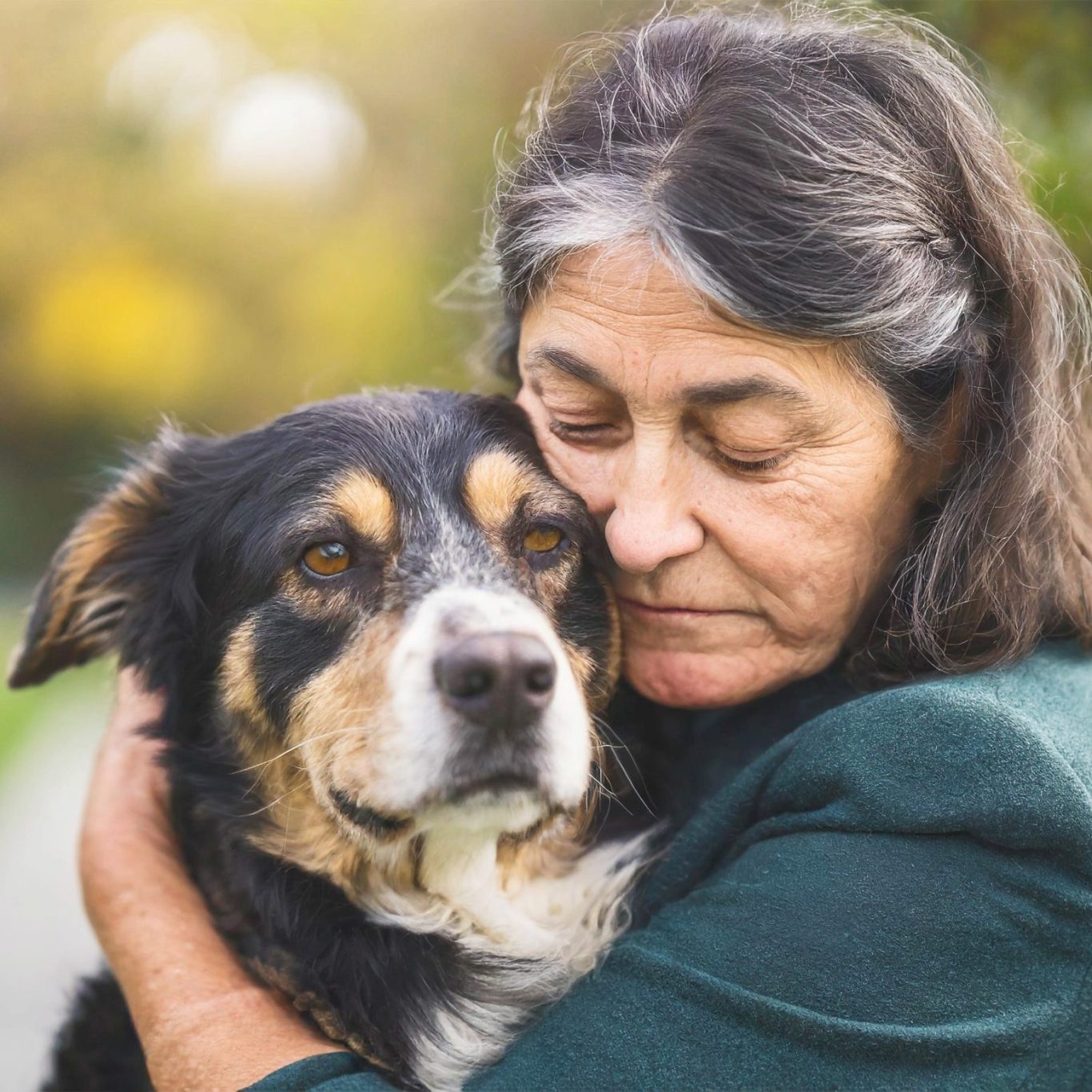 A woman embraces her dog, both showing love and affection in a serene outdoor setting.